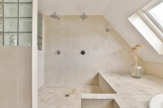 A sleek, minimalist bathroom featuring neutral tiles, a spacious layout, and natural light streaming through a skylight, enhancing the serene atmosphere.