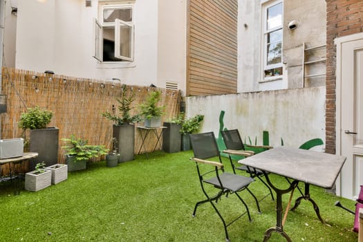 A serene outdoor patio featuring green artificial grass, decorative plants, and seating arrangements for relaxation or gatherings.