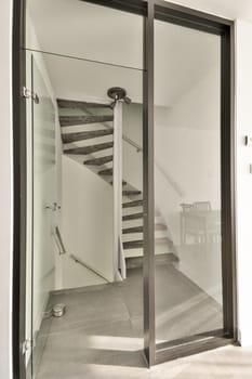 A sleek glass entrance leads to a stylish staircase, featuring minimalist design elements and a clean aesthetic, enhancing the modern interior space.