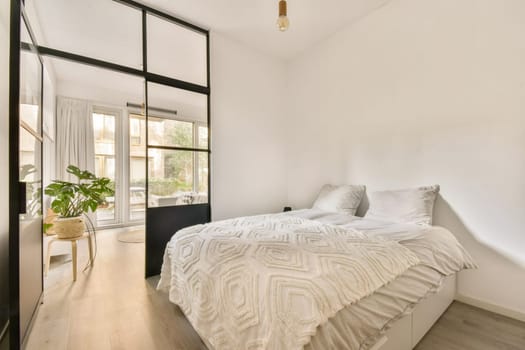 Bright and cozy bedroom featuring a large window, minimalist decor, and a touch of greenery, creating a tranquil atmosphere for relaxation.