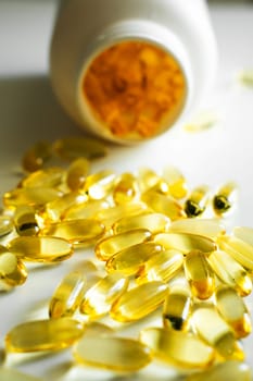 Gel capsules omega-3 laying near a white bottle on white background. Nutritional supplement