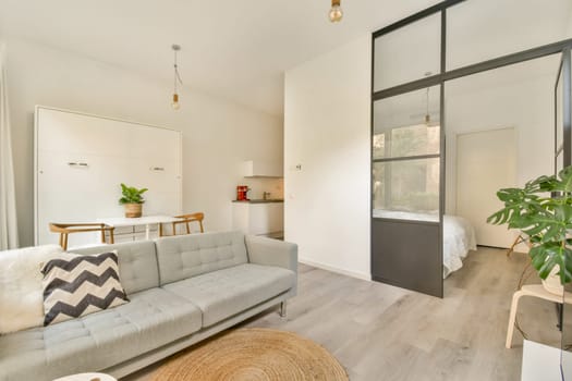 An elegant and modern living room featuring a stylish gray sofa, minimalist decor, and bright natural light, creating a warm and inviting atmosphere.