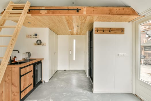 A sleek and modern interior featuring wooden accents, a ladder leading to an upper level, and minimalist decor that enhances the spacious feel of the area.