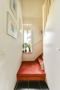 A well-lit hallway showcasing artistic frames and a cozy carpet, leading to a stairway. The ambiance is warm and thoughtfully designed for welcoming visitors.