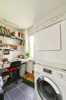 A well-organized modern home office featuring a desk, bookshelves, and a washing machine, showcasing a functional dual-use space.
