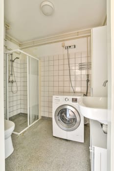 A sleek and minimalist bathroom featuring a washing machine, shower area, and clean lines. The bright space emphasizes functionality and modern design.