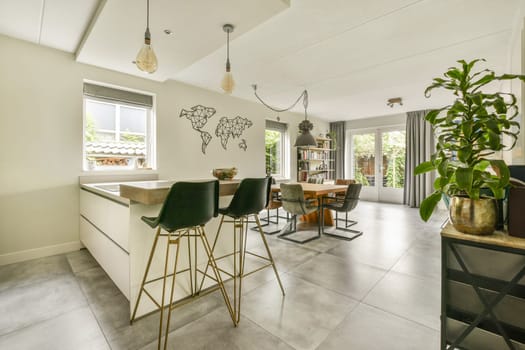 A stylish kitchen and dining space featuring a world map on the wall, modern furniture, and natural light streaming through windows, creating a warm atmosphere.