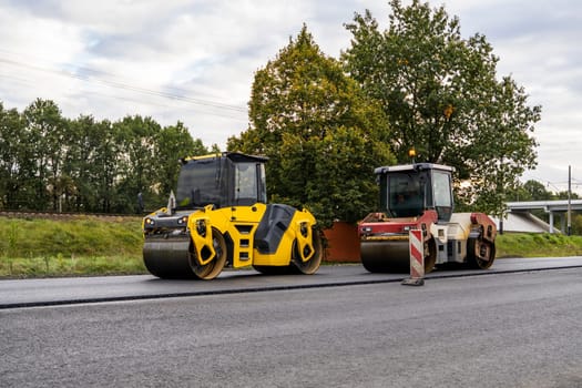 Two Heavy Asphalt Road Roller with heavy vibration roller compactor that press new hot asphalt on the roadway on a road construction