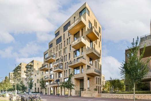 A contemporary architectural structure featuring unique geometric shapes and earthy tones, situated in an urban environment with greenery.