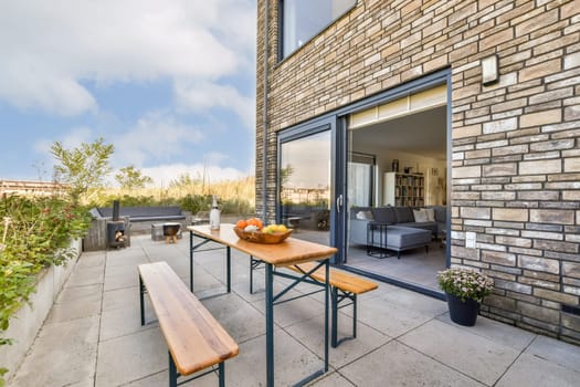 Stylish patio featuring a wooden dining table with fresh fruits, surrounded by greenery and contemporary furniture, ideal for outdoor gatherings.