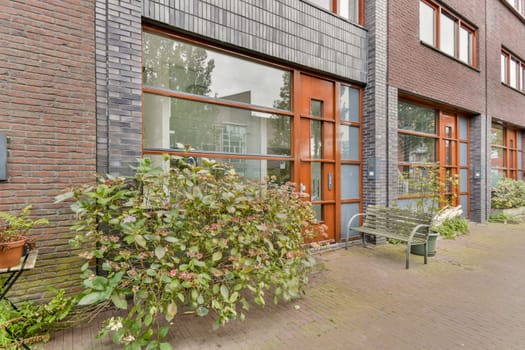 A contemporary building facade featuring large windows, brick walls, and surrounding greenery that harmonizes with the urban environment.
