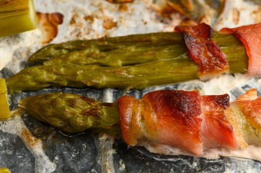 Fresh asparagus is wrapped in crispy bacon, grilled to perfection, and served at a lively summer barbecue. Friends and family gather, enjoying the vibrant flavors in a cozy backyard setting.
