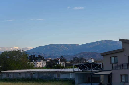 A peaceful village rests beneath the majestic mountains, showcasing a harmonious blend of nature and architecture. The soft evening light casts a calming ambiance over the scene.