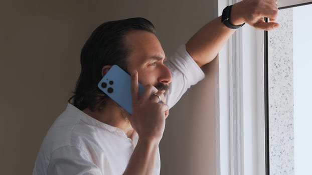 A relaxed yet attentive individual conducts a phone call by the window, exuding professionalism and calm confidence.