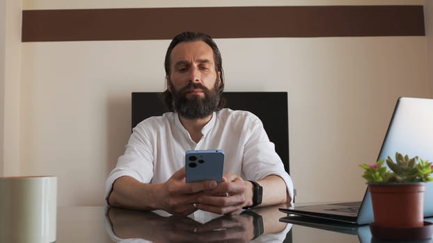 A confident entrepreneur seated at an organized desk, engaged with his digital devices in a modern workspace, demonstrating a productive atmosphere.