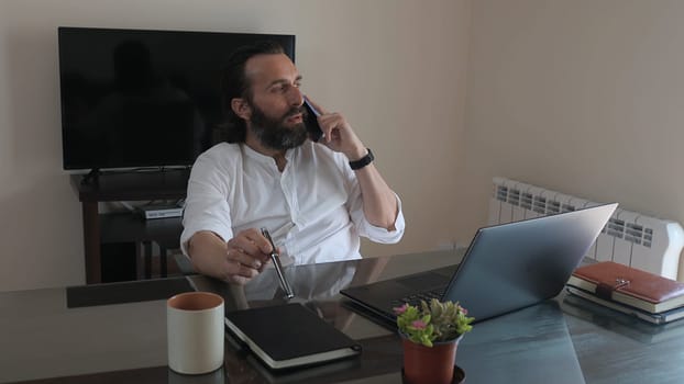 A confident entrepreneur working remotely in a sleek office setting. Engaged in conversation while using technology to conduct business, showcasing professionalism in a relaxed environment.