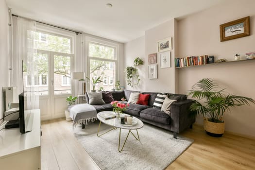 A cozy modern living room featuring large windows that fill the space with natural light, stylish furniture, and decorative plants adding a fresh ambiance.