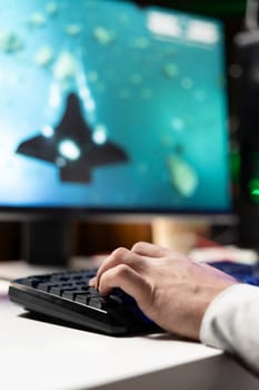 Man using gaming keyboard to fly spaceship in SF videogame, close up. Player using powerful PC and computer peripherals to compete in online science fiction multiplayer game competition