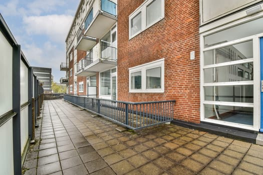 A contemporary apartment building featuring a brick facade and a paved pathway leading up to it, complemented by a clear sky in the background.