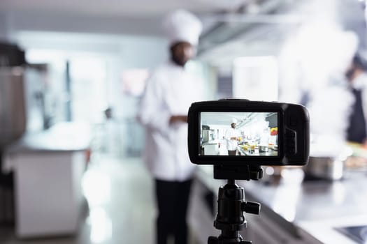 African american chef teaches his audience cooking skills on a video, explaining preparation methods and plating techniques. Expert hosting virtual classroom for online culinary training.