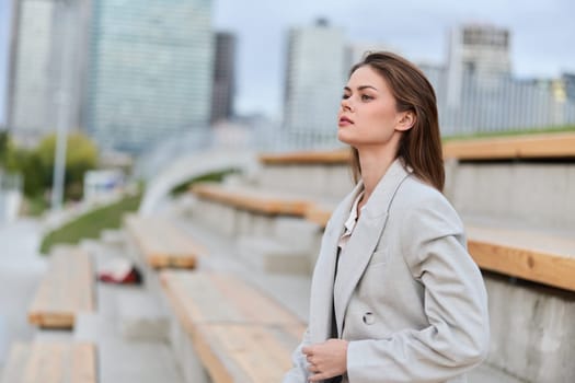 Portrait of a businesswoman in a gray blazer, exuding confidence and ambition against an urban skyline, perfect for conveying modern professionalism and success.