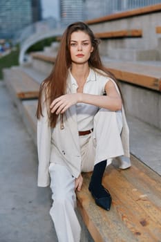 A poised woman in business attire sitting on wooden steps, exuding confidence with long hair and a calm demeanor, ideal for corporate and professional themes.
