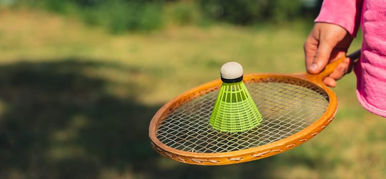 Woman hand holding wooden Badminton racket and shuttlecock. Outside recreation and fresh air. Healthy lifestyle nature connection sport summer activities. Stress relief hobby healthcare