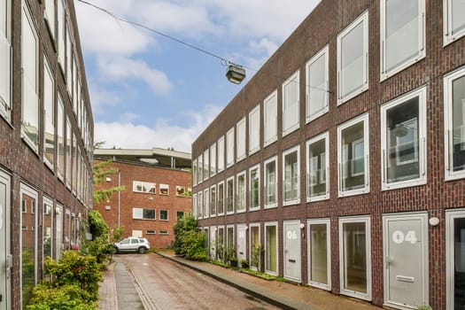 A modern architectural view showcasing a sleek building design and a conveyor system in an urban setting, surrounded by greenery and clear skies.
