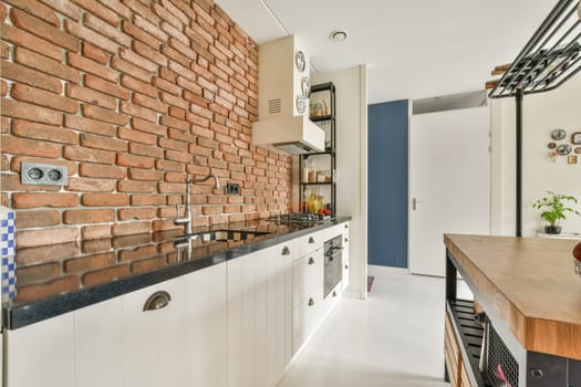 A stylish modern kitchen featuring exposed brick walls, sleek cabinetry, and minimalistic decor. The design offers a blend of rustic and contemporary aesthetics.