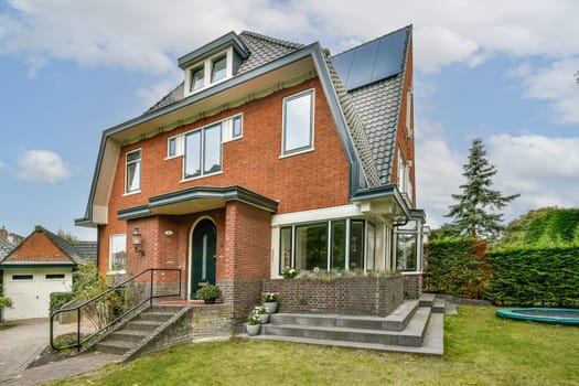 A contemporary brick house featuring large windows, a neatly landscaped lawn, and a minimalist design. Includes outdoor stairs and a serene environment.