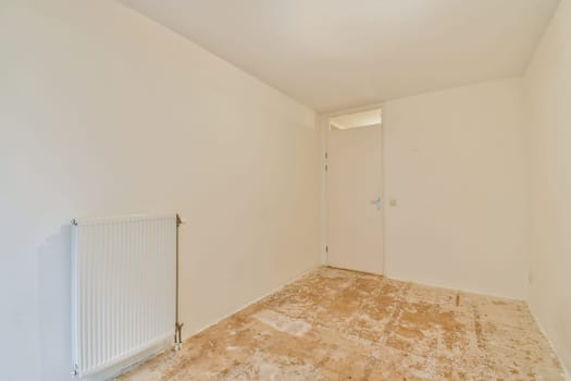 A spacious yet empty room featuring white walls and a bare floor, showcasing an open door and a radiator. The simplicity reflects a minimalist aesthetic.