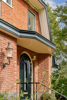 A picturesque brick home showcasing elegant architecture, complemented by lush bushes and trees in the surrounding garden.