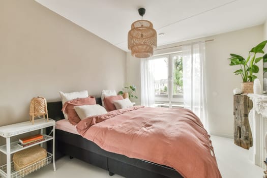 A stylish bedroom featuring a comfortable bed, soft bedding, and natural light illuminating the space. Green plants add a touch of freshness to the decor.