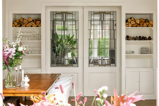 Stylish interior featuring glass paneled doors, organized shelves, and floral arrangements enhancing the overall ambiance and design.