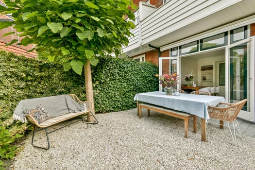 A beautifully designed outdoor patio featuring greenery, a table set for dining, and comfortable seating, providing a serene space for relaxation.
