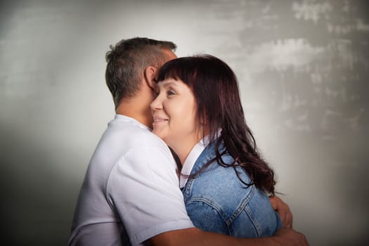 A middle-aged couple embraces warmly indoors, capturing their deep affection for each other in a cozy apartment setting.