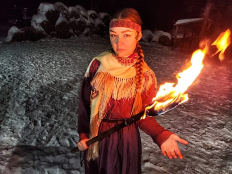 Actors in vibrant ethnic costumes showcase a mesmerizing fire performance under the starry winter sky, embodying Viking spirit and bravery.