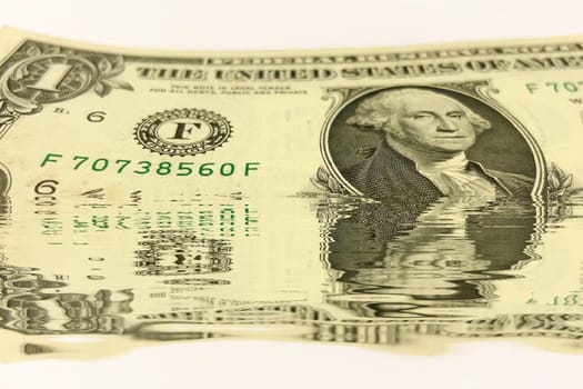 Creative conceptual image of US dollar bills partially submerged in water with a water reflection effect. Symbolizes financial crisis, liquidity problems, or a fluctuating economy. Ideal for articles or graphics related to money, finance, economics, or global markets.