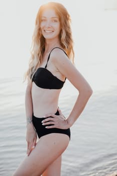 Woman in black swimsuit sunbathing and swimming on the beach by the sea