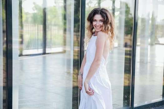 Portrait of a woman smiling in a light summer dress in the park on a walk