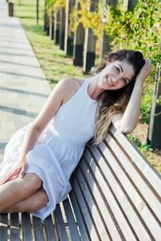 Portrait of a woman smiling in a light summer dress in the park on a walk