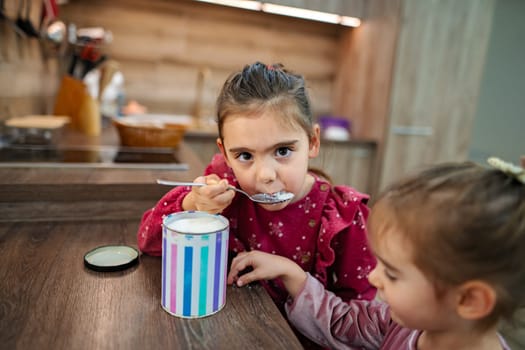 Two young girls are in a warm and inviting kitchen, sharing a fun moment.