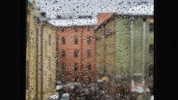 Raindrops sliding on window glass blurring buildings in the background creating an abstract texture