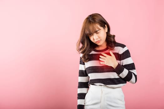 Young woman pressing on chest pain isolated on pink background, painful expression heartache, female having heart attack heart disease, Painful cramps