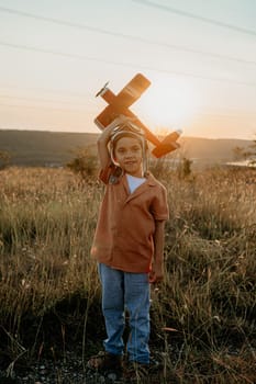 Smiling curious 5 years old preschool child boy plays with craft wooden retro styled airplane toy, discovering future profession interest, dreamer kid flying, traveling. High quality photo