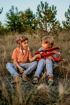 Smiling curious 5 years old preschool children boys playing, discussing aviation with craft wooden retro styled airplane toy, discovering future profession interests dreamer kids flying, traveling.
