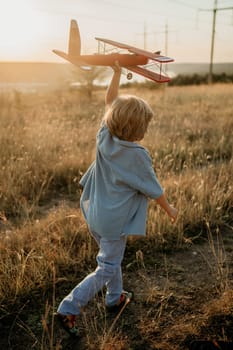 Unrecognizable 5 years old child boy running with wooden vintage airplane. Kid dreaming to be pilot. Imagination freedom, travel everywhere, active childhood. High quality