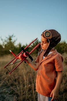 Smiling curious 5 years old preschool child boy plays with craft wooden retro styled airplane toy, discovering future profession interest, dreamer kid flying, traveling. High quality photo
