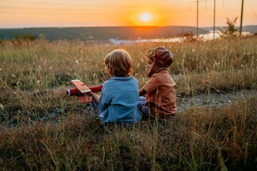 Smiling interested friends brothers, cute boys plays, talks about aviation with handmade wooden vintage plane toy, discovering future pilot profession interests, dreamers kids flying, traveling.