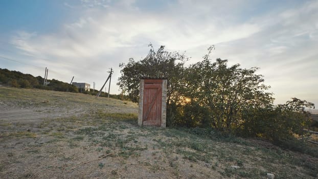 Old wooden toilet standing on a hill in Crimea at sunset near Belogorsk
